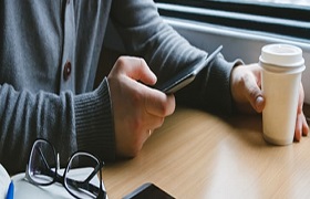 a man checks his phone while enjoy a coffee